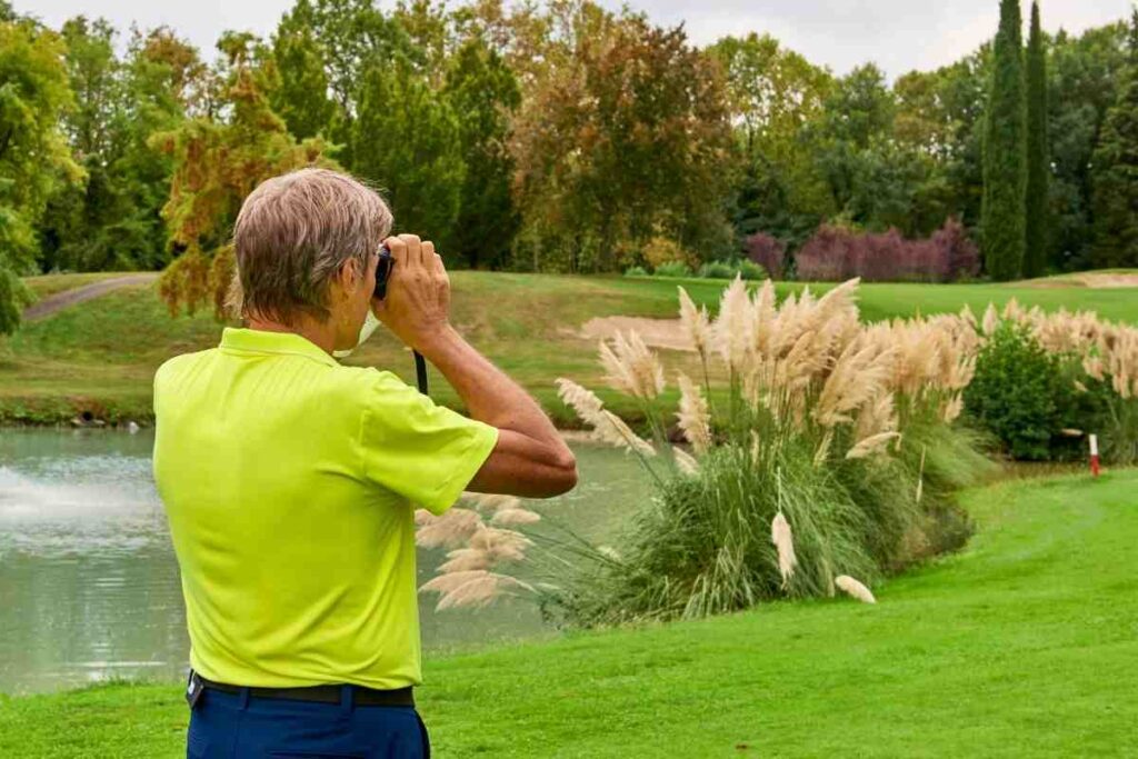 golfista usando un telémetro de golf para medir la distancia